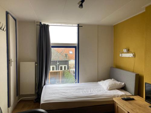a bedroom with a bed and a large window at RB Hostel in Zierikzee