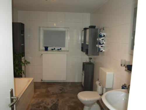 a bathroom with a toilet and a tub and a sink at Ferienwohnung Ebbe in Attendorn