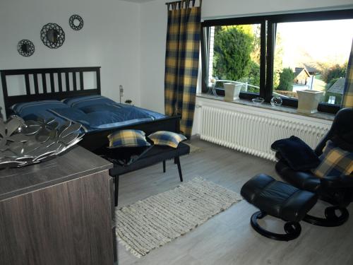 a bedroom with a bed and a chair and a window at Ferienwohnung Ebbe in Attendorn