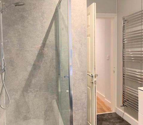 una ducha con puerta de cristal en un baño en Beach Apartment - Seafront Apartment, en Filey
