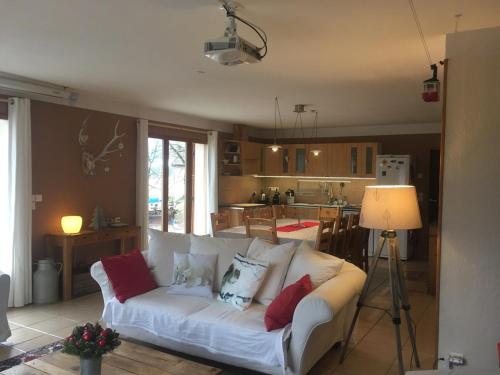 een woonkamer met een witte bank en een keuken bij Le Cerf d'Argent in Saint-Andéol
