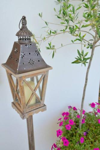 a wooden lantern on a wooden pole next to flowers at L'olivier Milos in Plaka Milou