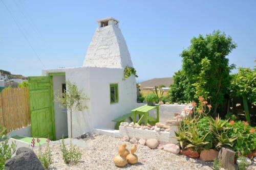 a garden with a small white house and some plants at L'olivier Milos in Plaka Milou