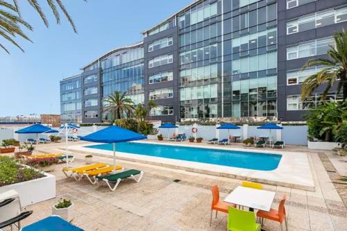 a swimming pool with tables and chairs and a building at Neptune Suite-Hosted by Sweetstay in Gibraltar