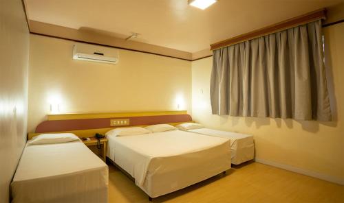 um quarto de hotel com duas camas e uma janela em Hamburgo Palace Hotel em Balneário Camboriú