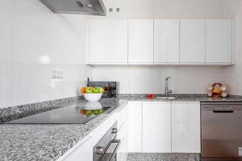a white kitchen with a bowl of fruit on the counter at Camas casa a 5 min de Sevilla con piscina in Camas