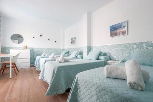 a bedroom with three beds and a desk and a table at Camas casa a 5 min de Sevilla con piscina in Camas