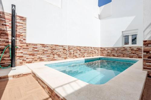 a swimming pool in a house with a brick wall at Camas casa a 5 min de Sevilla con piscina in Camas
