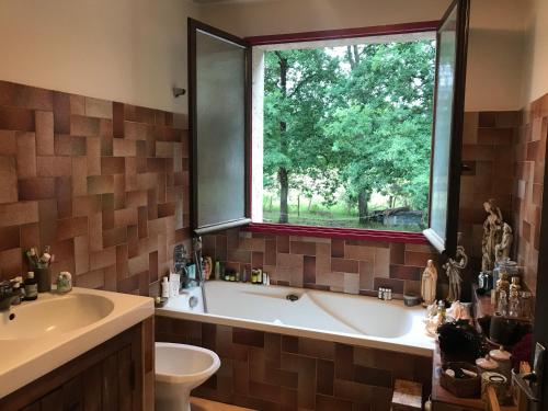 La salle de bains est pourvue d'une baignoire, d'un lavabo et d'une fenêtre. dans l'établissement Au Pain des Anges, à Saint-Gervais en-Belin