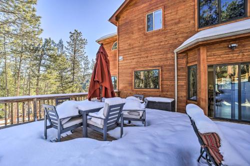 a deck with a table and chairs in the snow at Expansive Evergreen Home with Hot Tub and Deck! in Evergreen