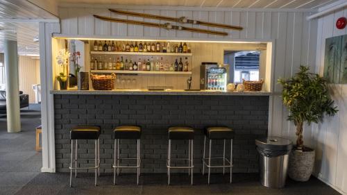 Um bar com quatro bancos à frente. em Austbø Hotell em Rauland