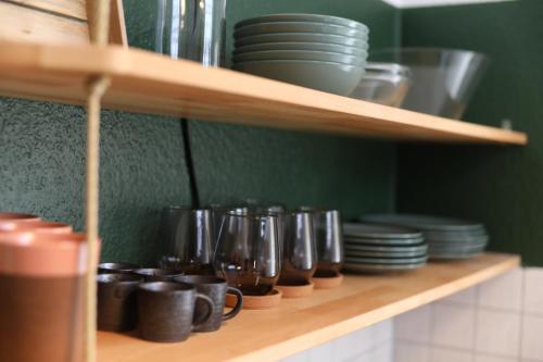a shelf with plates and cups and dishes on it at Urban Lodge Erlangen I Superzentral I Free Parking I WLAN I Netflix in Erlangen
