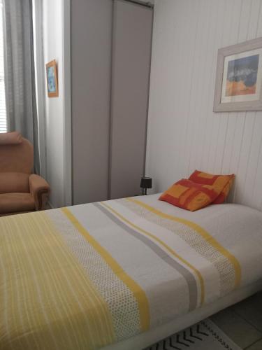 - un lit avec une couverture jaune et blanche et une chaise dans l'établissement Nid douillet, à Vals-les-Bains
