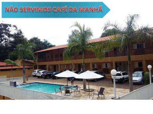 een hotel met een zwembad en tafels en parasols bij POUSADA RECANTO DO TRABALHADOR in Rancharia