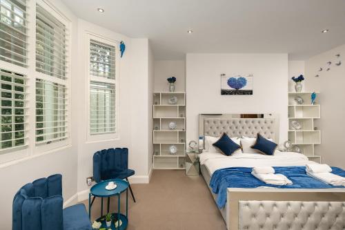 a bedroom with a bed and two blue chairs at დLUXURY & Spacious Duplex in the Heart of Chelseaდ in London