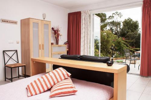 Cette chambre comprend un lit, une table et une fenêtre. dans l'établissement Moinho Da Asneira - Duna Parque Group, à Vila Nova de Milfontes