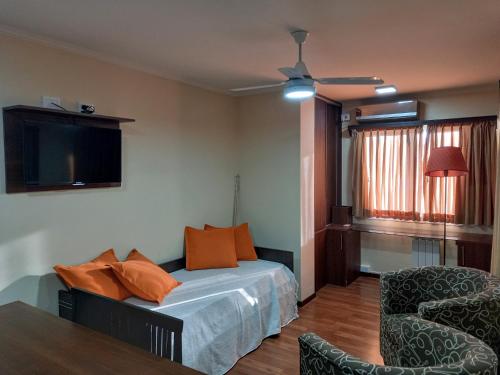 1 dormitorio con 1 cama, 1 silla y TV en MIRALEJOS 6 CENTRO en Villa Carlos Paz