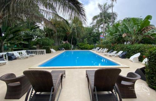 a swimming pool with lounge chairs and a swimming pool at Tropical Garden Hotel in Jacó