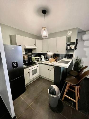 a kitchen with white cabinets and a black refrigerator at La nature aux portes de Toulouse in Pinsaguel