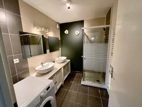 uma casa de banho com 2 lavatórios e uma máquina de lavar roupa em La nature aux portes de Toulouse em Pinsaguel