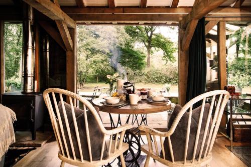a table and two chairs in a room with a table and a window at Luxury Boltholes cabin in the woods with hot tub in Five Oaks
