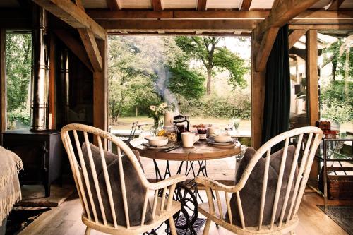 a table and two chairs in a room with a table and a window at Luxury Boltholes cabin in the woods with hot tub 