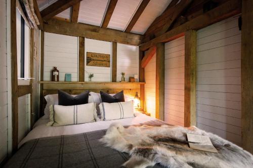 1 dormitorio con 1 cama en una habitación con paredes de madera en Luxury Boltholes cabin in the woods with hot tub, 
