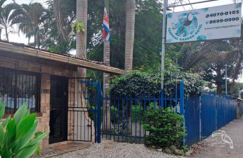a building with a blue gate and a sign at Tropical Garden Hotel in Jacó