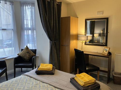a hotel room with a bed and a desk and a mirror at THE PROMENADE SUITE - 2 min walk to the lovely beach front promernade of llandudno in Llandudno