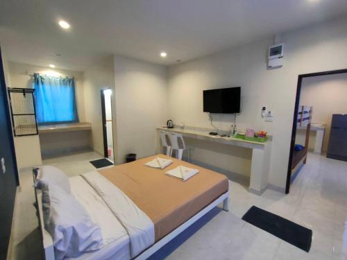 a bedroom with a bed and a desk with a television at Banana Resort Sadao in Sadao