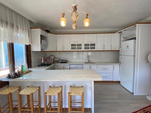 a kitchen with white cabinets and a island with bar stools at Doğa ile baş başa kalabileceğiniz, sakin kırevi in Rize