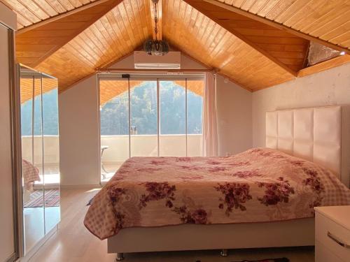 ein Schlafzimmer mit einem Bett und einem großen Fenster in der Unterkunft Doğa ile baş başa kalabileceğiniz, sakin kırevi in Rize