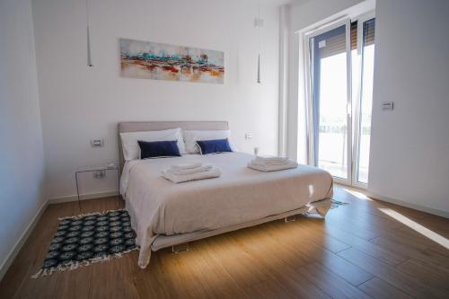 una camera bianca con un grande letto e una grande finestra di Rossani Suites&Aparts a Bari