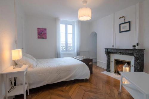 une chambre blanche avec un lit et une cheminée dans l'établissement La Place Gourmande, à Mâcon