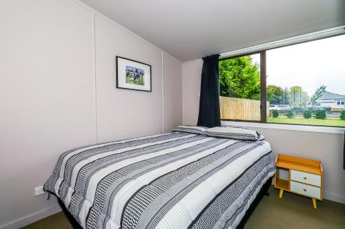 a bedroom with a bed and a window at Methven Ski Bach With Sleepout in Methven