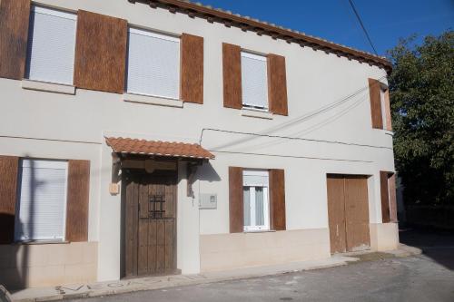 a white house with wooden windows and doors at CASA RURAL VEGASAN in Santa Colomba de la Vega
