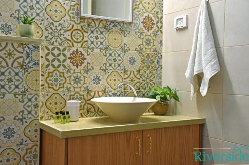 uma casa de banho com um lavatório e uma parede de azulejos em Riverside em Majdal Shams