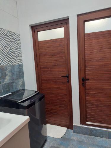 two wooden doors in a bathroom with a sink at The Light Villa Flic en Flac LICENSED BY TOURISM AUTHORITY 16609 in Palmyre
