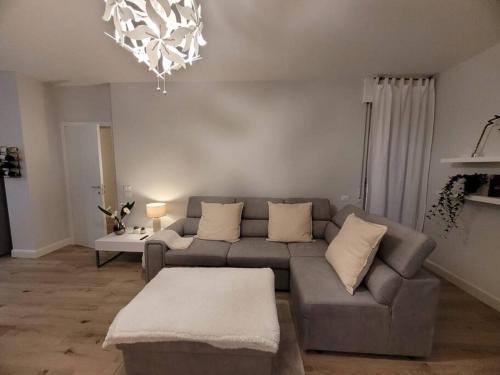 sala de estar con sofá gris y lámpara de araña en View lovely 3bed-2bath condo full furnished., en Vittorio Veneto
