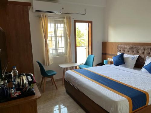 Una habitación de hotel con una cama, una mesa y sillas. en NP Royal INN, en Bangalore