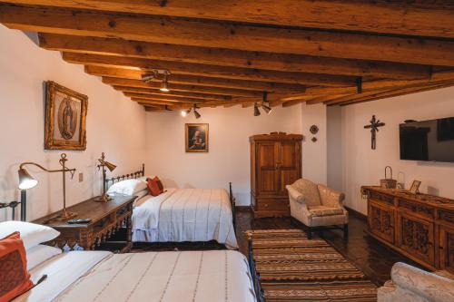 a bedroom with two beds and a tv in it at El Edén Hotel Boutique in Pátzcuaro