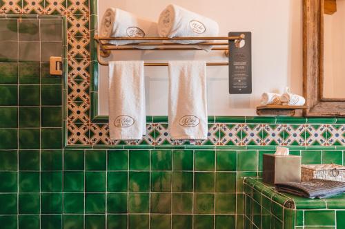 - une salle de bains carrelée de vert avec deux miroirs et des serviettes dans l'établissement El Edén Hotel Boutique, à Pátzcuaro