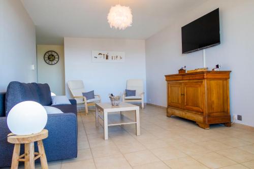 uma sala de estar com um sofá azul e uma televisão em Côté mer em Marselha