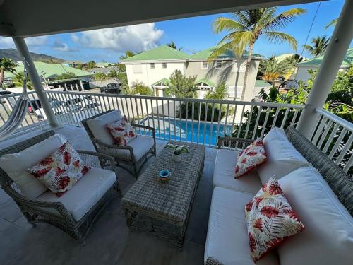 a porch with a couch and chairs and a table at Orient Bay, Appartement Héliconia. in Orient Bay