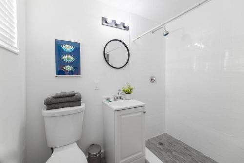 ein weißes Bad mit einem WC und einem Spiegel in der Unterkunft Fantastic studio near the beach in Miami