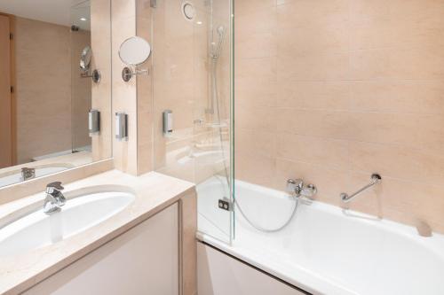 La salle de bains est pourvue d'une baignoire, d'un lavabo et d'une douche. dans l'établissement Select Hotel Erlangen, à Erlangen