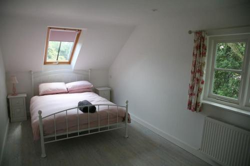 a bedroom with a bed with pink pillows and a window at The Paddocks in Pilsdon