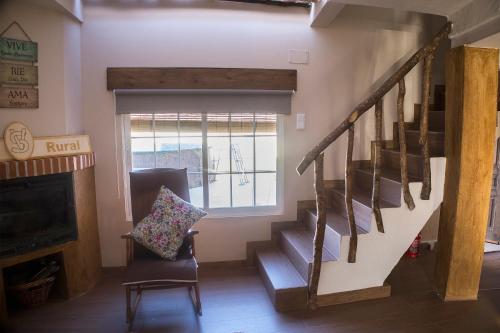 a living room with stairs and a chair and a window at CASA RURAL VEGASAN in Santa Colomba de la Vega