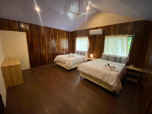 two beds in a bedroom with wooden walls and wood floors at Grand Park Manuel Antonio - Adults Only in Manuel Antonio