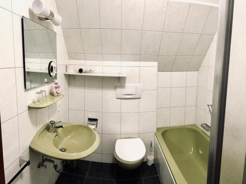 a bathroom with a sink and a toilet and a tub at Landhotel Laarmann in Lennestadt